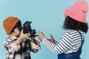 Multiracial children taking photo on retro instant photo camera